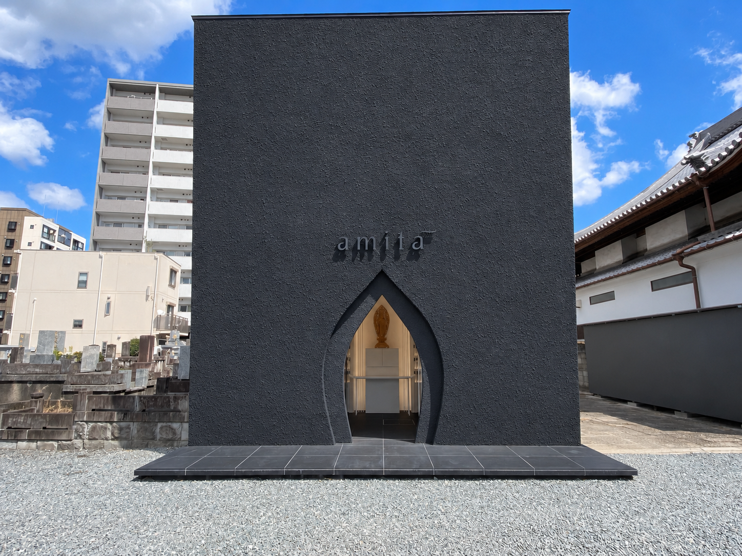 黒い外壁とアーチ形の入口がある納骨堂amitā